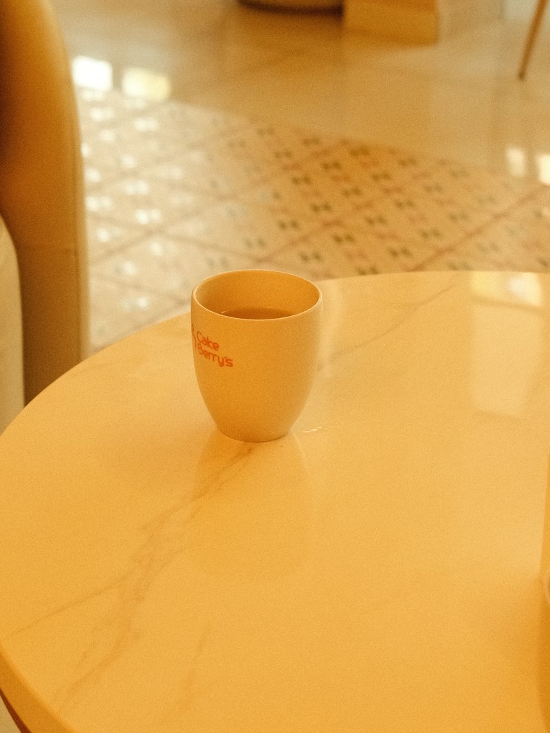 A white cup on a marble table in a softly lit indoor setting.