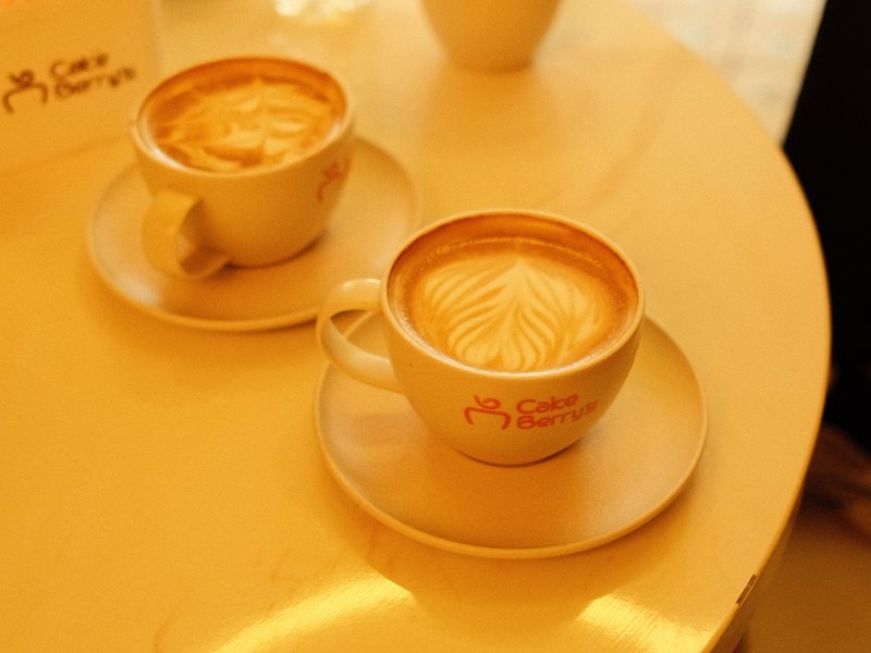 Two cups of latte art coffee on a light-colored table.