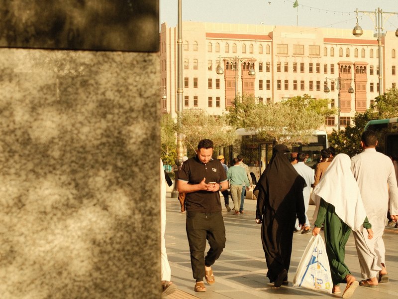 People walking in an urban setting with a building in the background during golden hour.