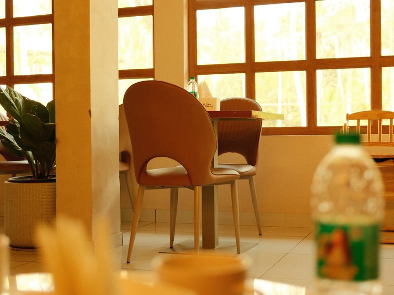 A cozy indoor dining area with wooden windows and a chair in focus, featuring a water bottle in the foreground.