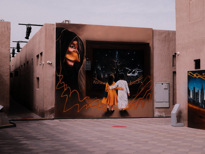 A mural depicting two figures walking towards a starry sky, surrounded by urban architecture.