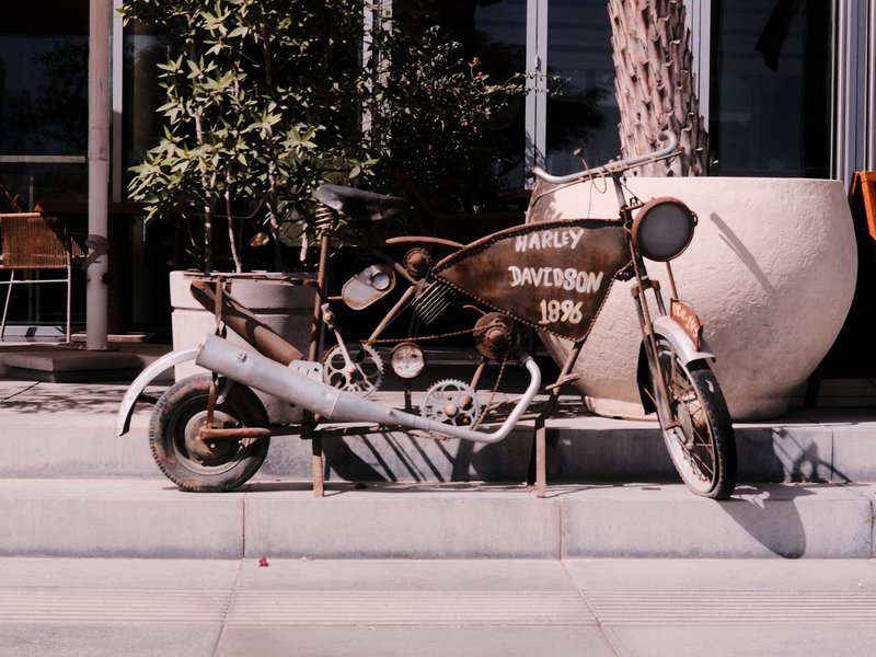A vintage motorcycle parked beside a large planter with greenery, showcasing a rustic charm.