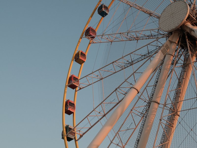 Close-up of a ferris wheel against a clear sky during sunset.