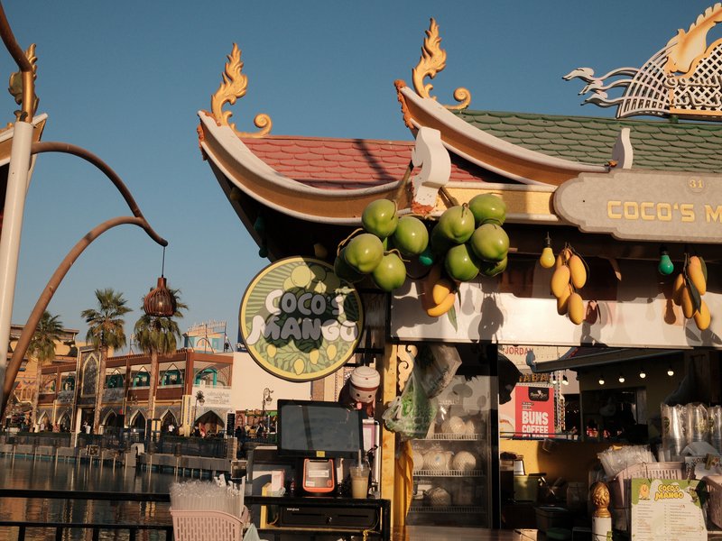 Colorful market stall with tropical fruits and decorative architecture under a clear blue sky.