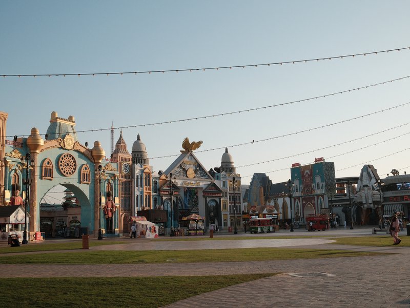 A colorful amusement park scene with whimsical architecture and rides under a clear sky.