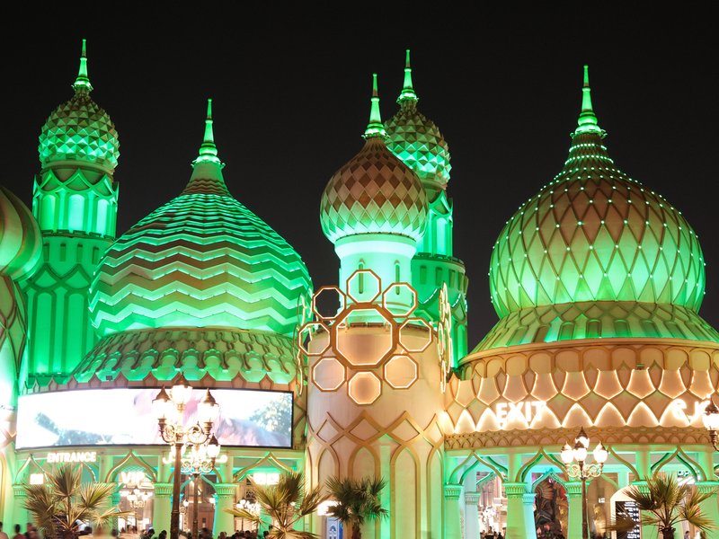 Colorful domes of a building illuminated in green light at night.