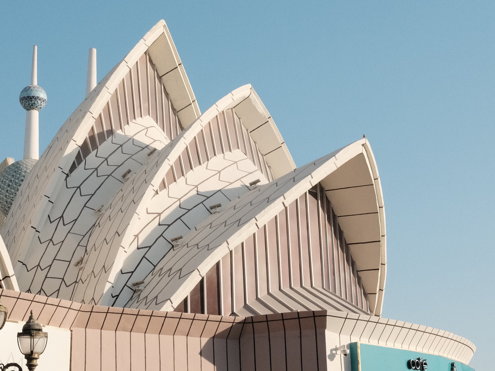 Close-up of a modern architectural structure with curved roofs against a clear blue sky.