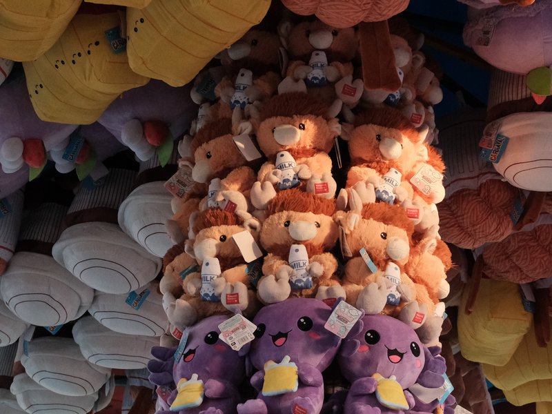 A colorful display of plush toys stacked in a store, featuring various characters and shapes.