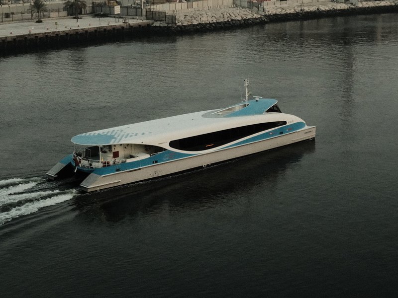 A sleek, modern ferry gliding through calm waters with a cityscape in the background.