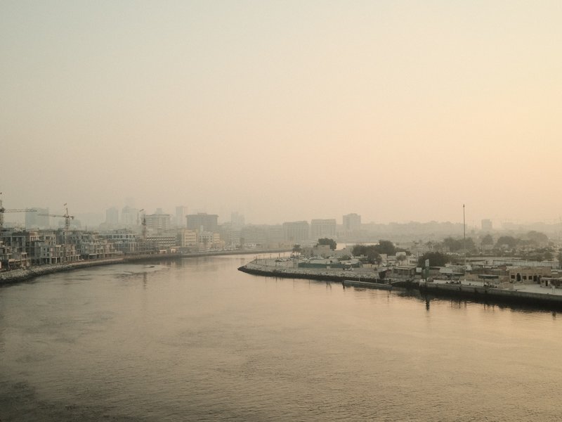A serene river scene at dusk with a hazy skyline and soft reflections on the water.