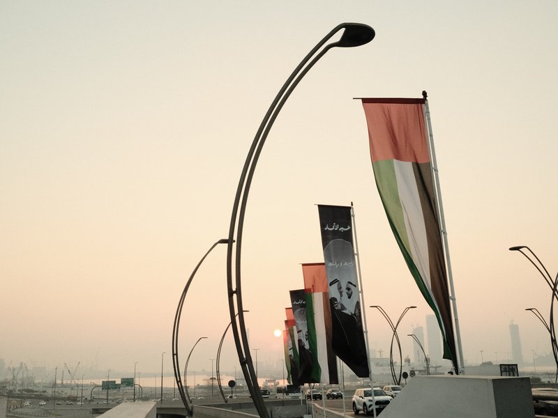 Colorful banners on poles against a soft pastel sky during sunset.