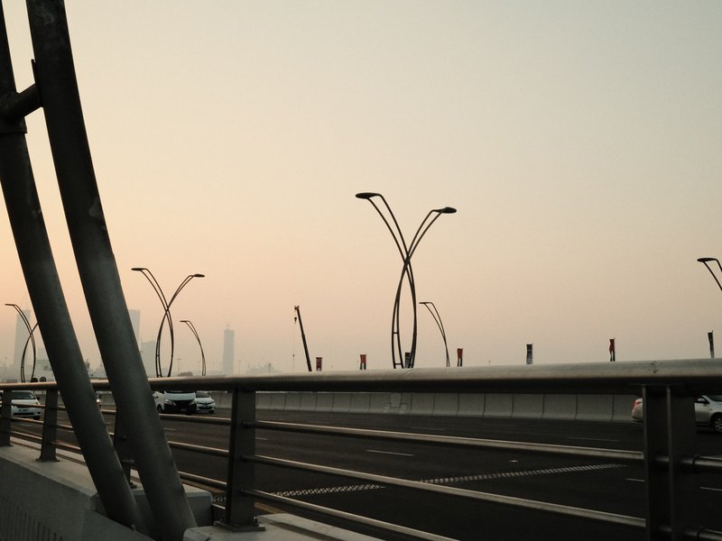 A hazy urban scene featuring unique streetlight designs along a highway at dusk.