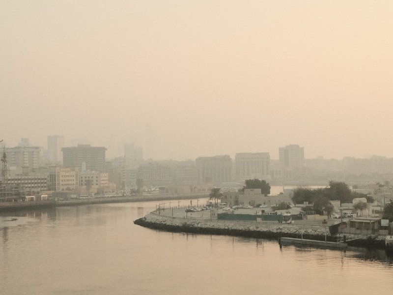 A hazy river scene with buildings in the background and a calm water surface reflecting the soft light.