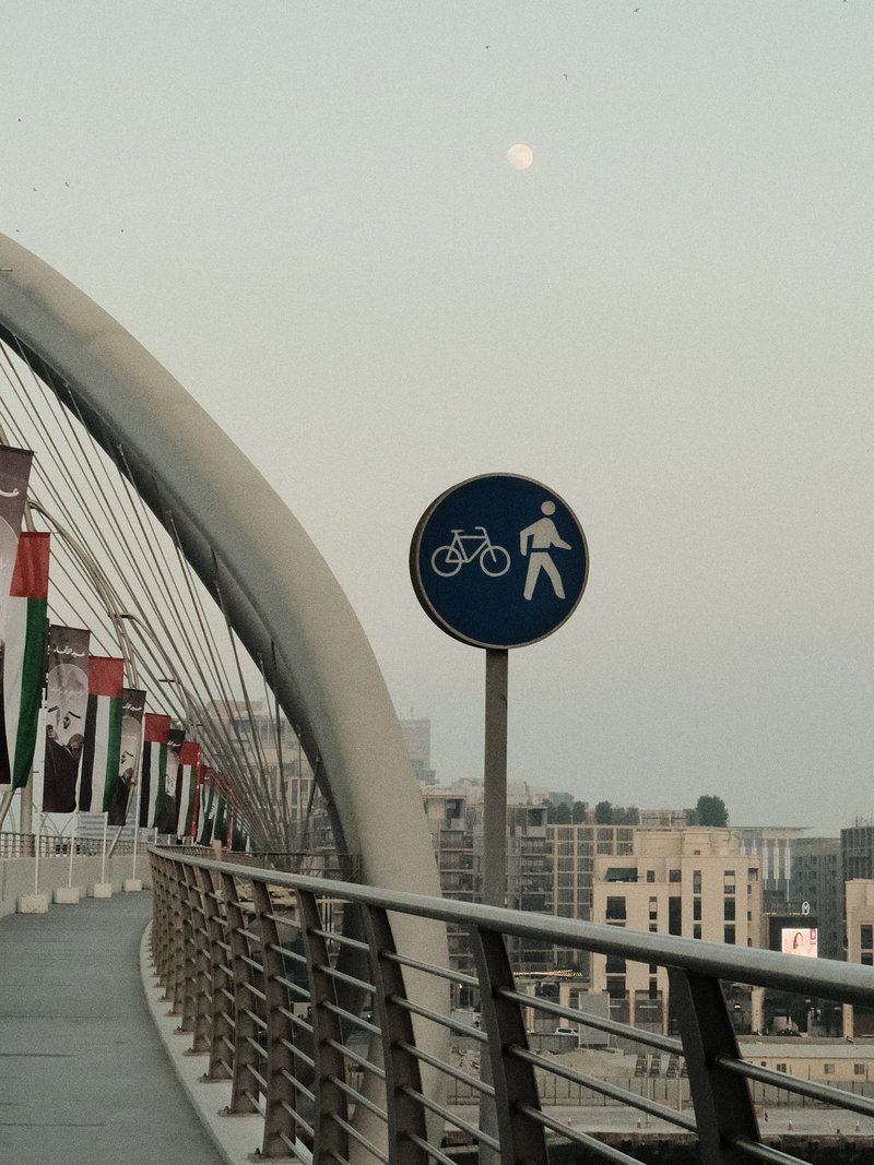 A pedestrian and bicycle sign on a bridge with a faint moon in the background.