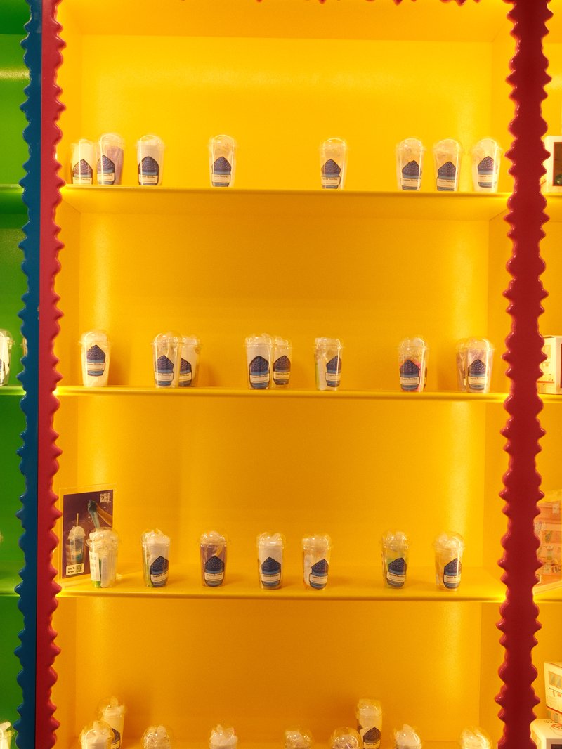 Colorful display of jars on shelves against a bright yellow background.