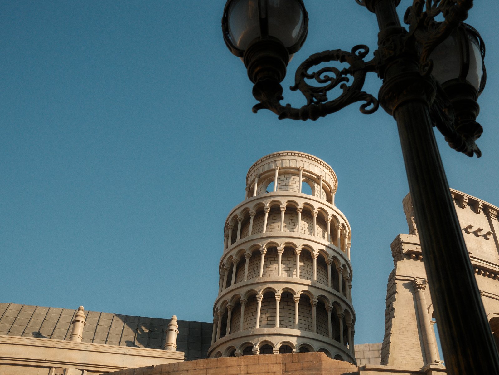 A close-up view of a historic tower with a clear blue sky in the background, featuring a decorative lamp post.
