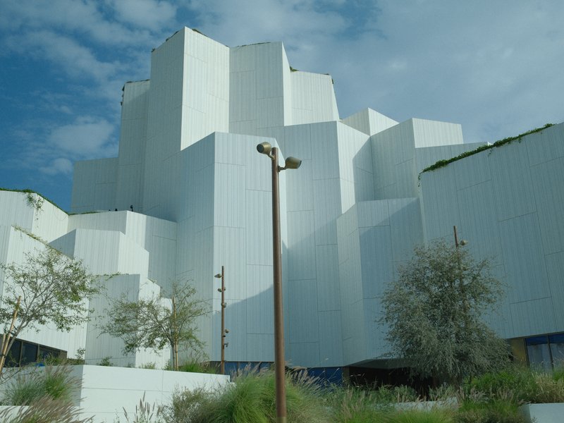 Abstract architectural structure with white geometric forms under a cloudy sky.