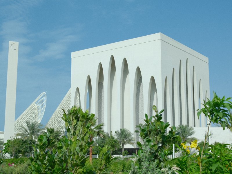 Modern architectural building with unique arches surrounded by greenery under a clear blue sky.