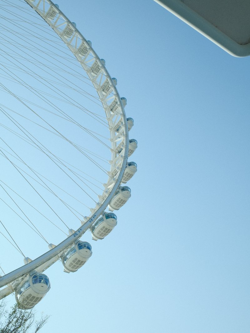 A close-up view of a ferris wheel against a clear blue sky, showcasing its structure and gondolas.