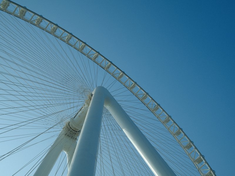 A low-angle view of a large ferris wheel against a clear blue sky.