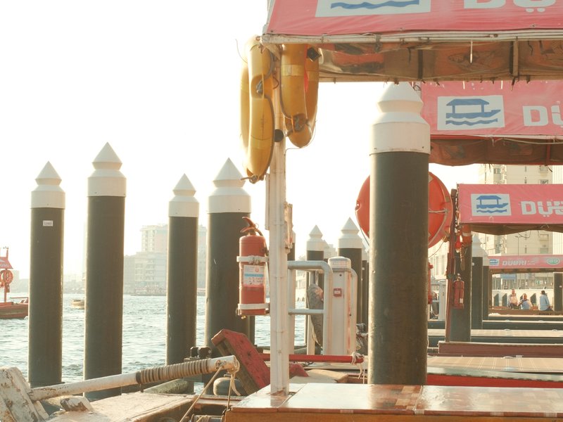 View of wooden docks with black and white poles, pink signage, and a hazy waterfront in the background.