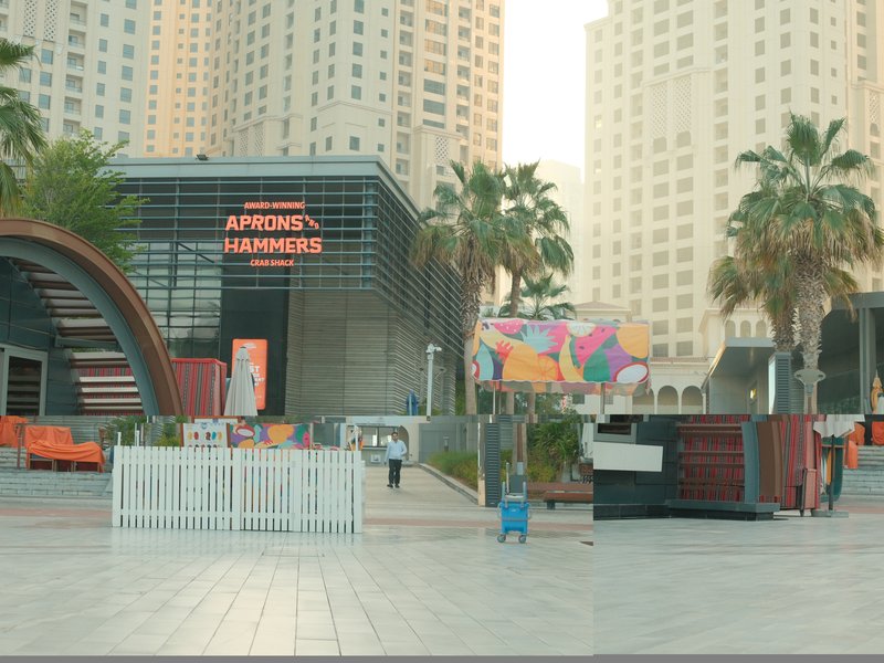 Urban scene featuring modern architecture with palm trees and colorful murals in a city setting.
