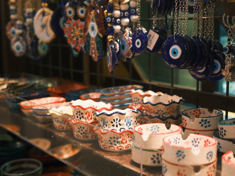 Colorful ceramic bowls and decorative items displayed on a shelf in a market.