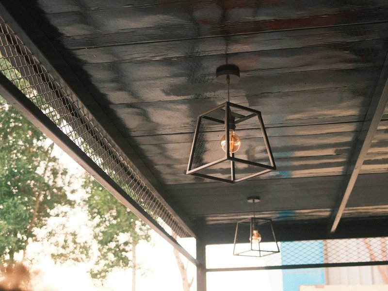 Interior view of a cafe with hanging light fixtures and a textured ceiling.