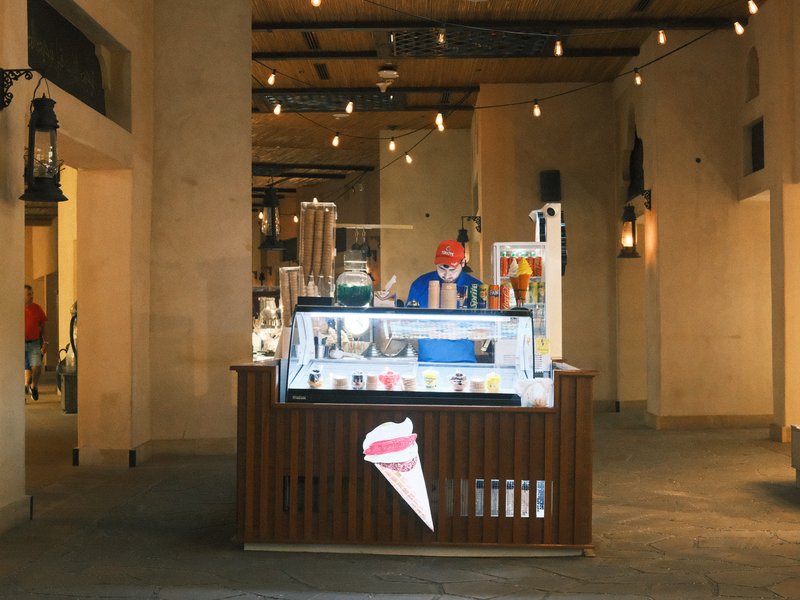 An ice cream stand in a well-lit indoor space with a vendor serving customers.