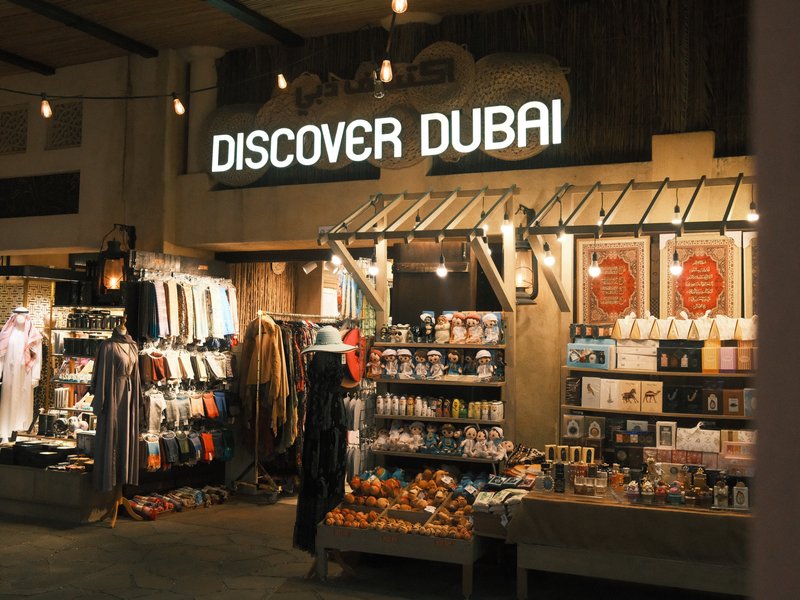 A shopfront displaying souvenirs and local products with a sign that reads 'Discover Dubai'.