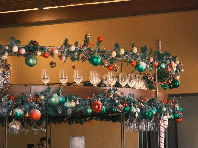 A festive bar display adorned with Christmas ornaments and glasses, creating a cheerful holiday atmosphere.