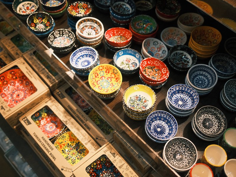 Colorful ceramic bowls and decorative plates arranged in a display case with warm lighting.