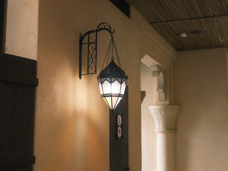 A decorative lantern hanging on a wall in a softly lit indoor corridor.