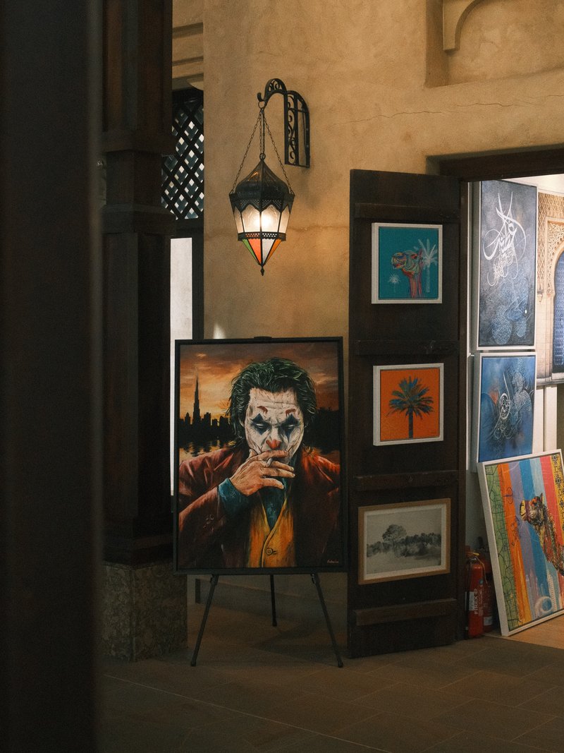 A vibrant painting of a character with a painted face, displayed in an art gallery setting.