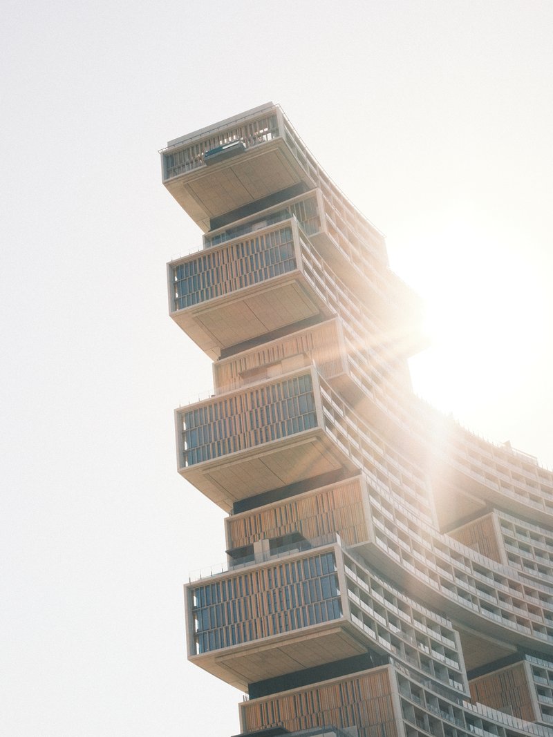 A modern architectural building with stacked levels, sunlight shining from behind.