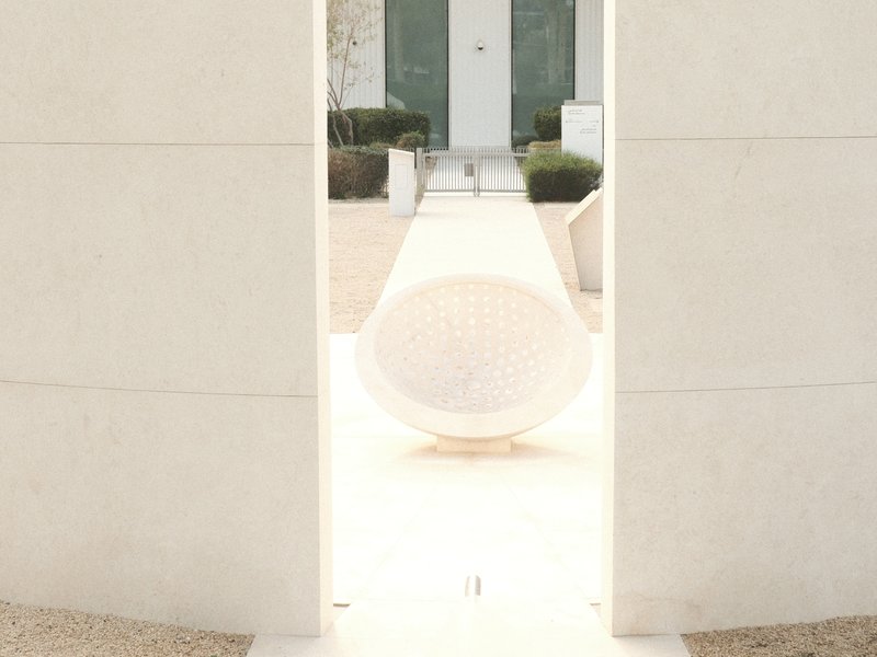 A modern architectural scene featuring a spherical object framed by a minimalist white structure.