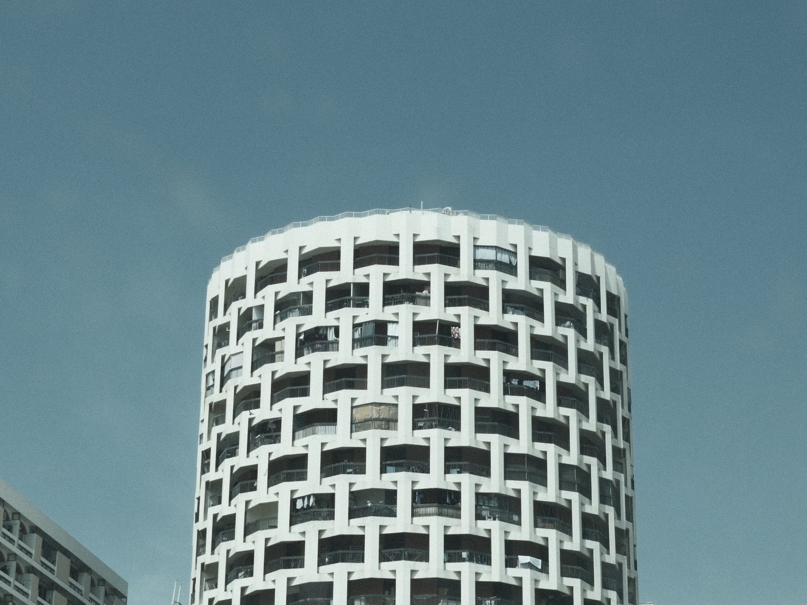 A modern circular building with a patterned facade against a clear blue sky.