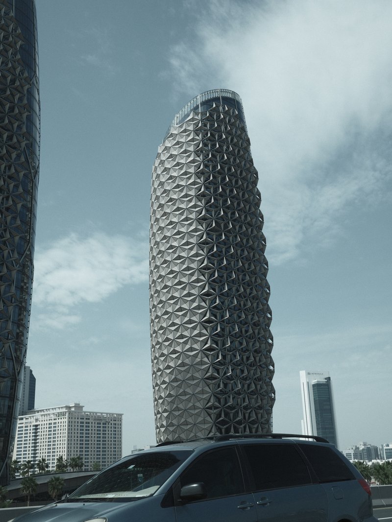 A modern architectural tower with a unique geometric design against a cloudy sky.