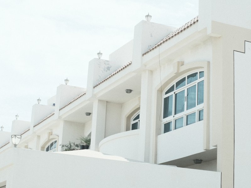 Close-up of a modern white building with curved balconies and decorative elements under a bright sky.
