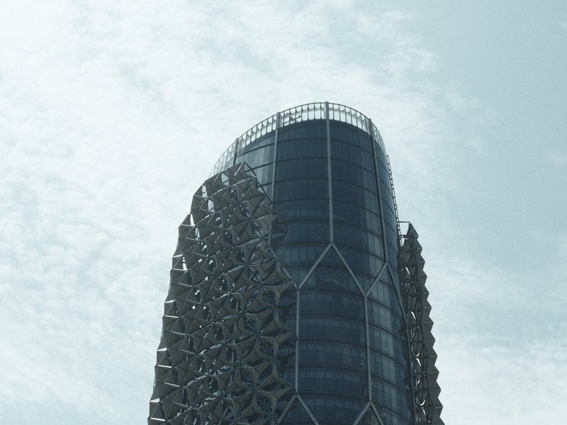 A modern architectural building with a unique geometric facade against a cloudy sky.