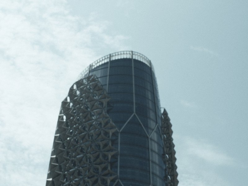 A modern skyscraper with a unique geometric facade against a cloudy sky.