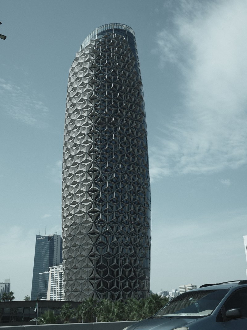 A modern skyscraper with a unique geometric facade against a blue sky.