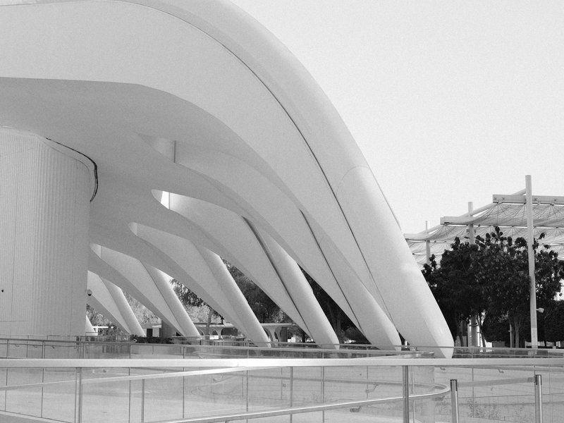 Curved white architectural structures with smooth lines and shadows in a modern urban setting.
