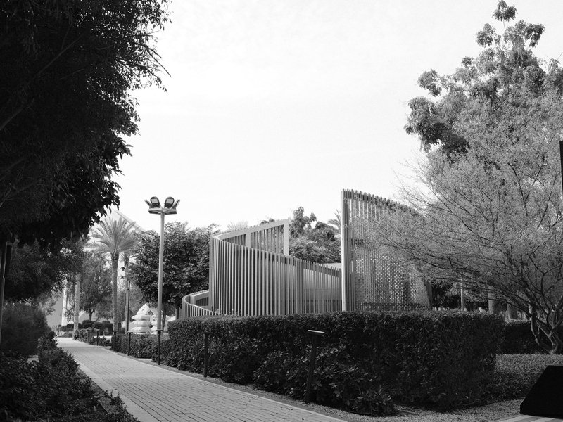 A modern architectural structure surrounded by greenery in a park setting.