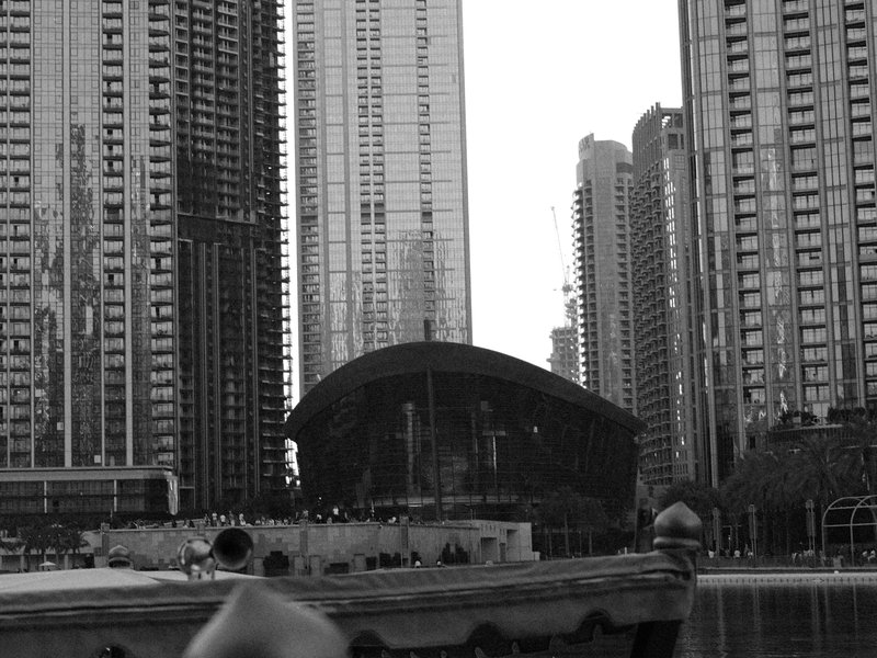 A view of modern skyscrapers surrounding a curved building near a waterway.