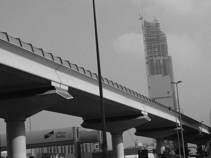 A low-angle view of a modern overpass with a skyscraper in the background, shrouded in mist.