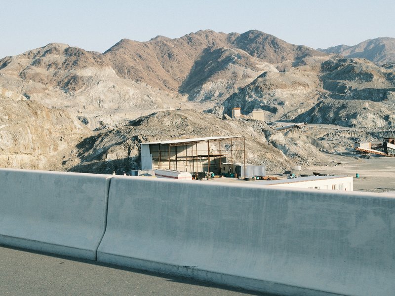 A barren landscape with mountains in the background and a concrete barrier in the foreground.