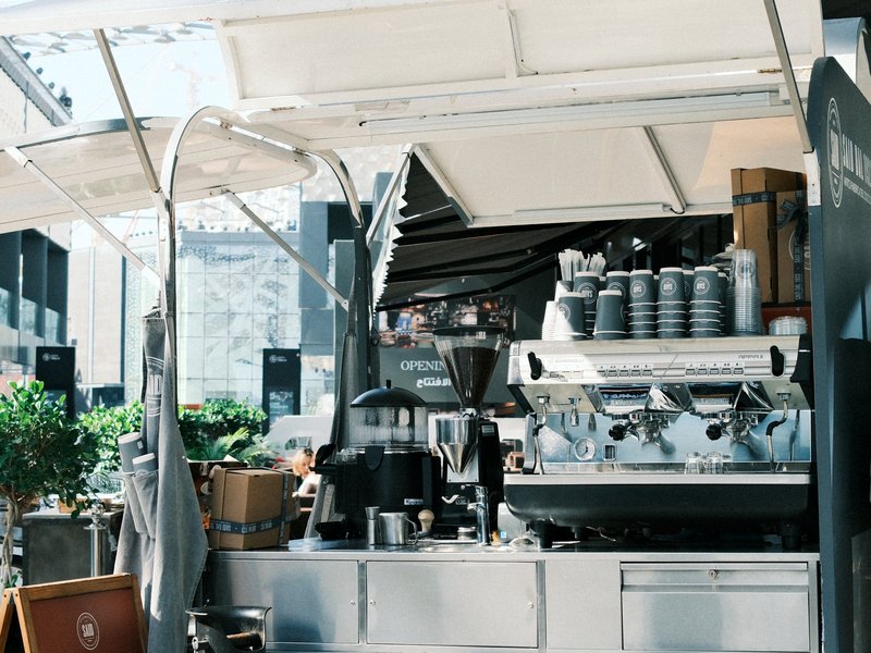 A modern coffee cart with espresso machines and coffee equipment in an urban setting.