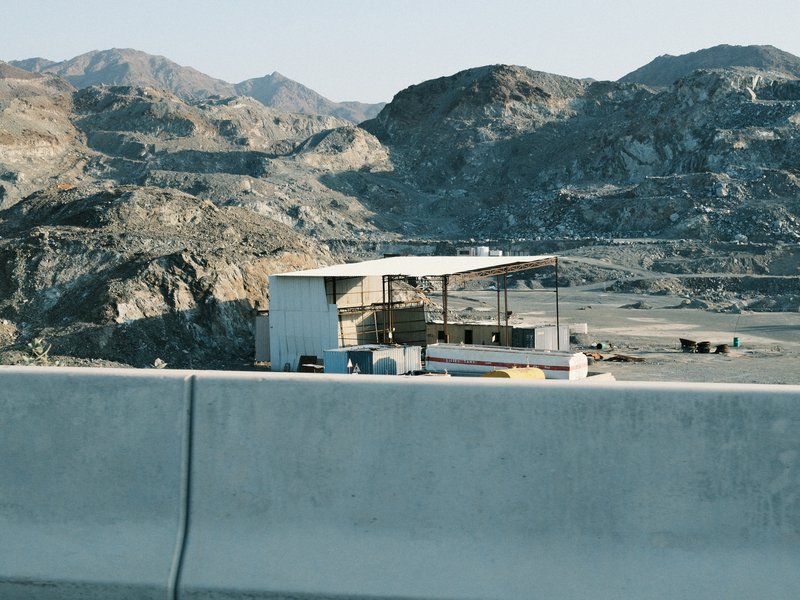 A small white structure near a rocky landscape with mountains in the background under clear skies.