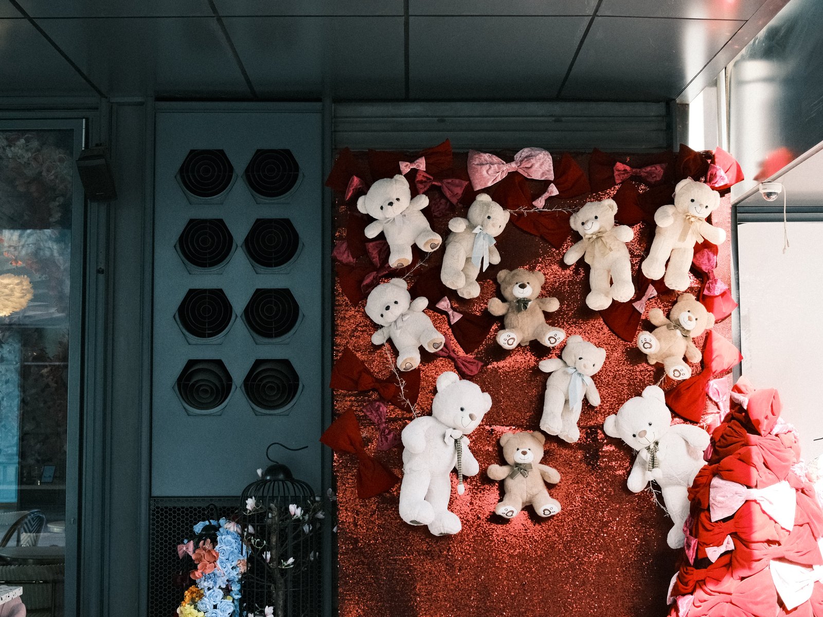 A display of teddy bears on a red backdrop with decorative elements and hats in the background.